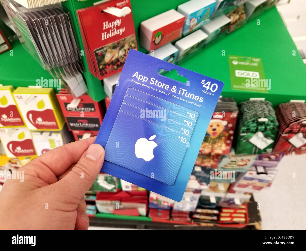 PLATTSBURGH, USA - Januar 21, 2019: Apple Itunes 40 dollar Geschenkkarte in eine Hand über ein Regal mit verschiedenen Geschenkgutscheinen in einem Walmart Stores. Stockfoto