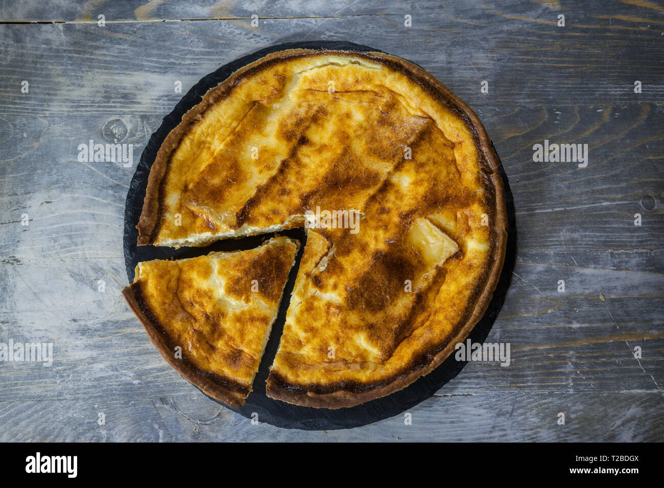 Traditionelle französische Quiche Lorraine pie aus Brie mit einem Stück geschnitten, von oben gesehen, auf Anzeige auf einem rustikalen Holztisch. Es ist eine Ikone Teller von Ea Stockfoto