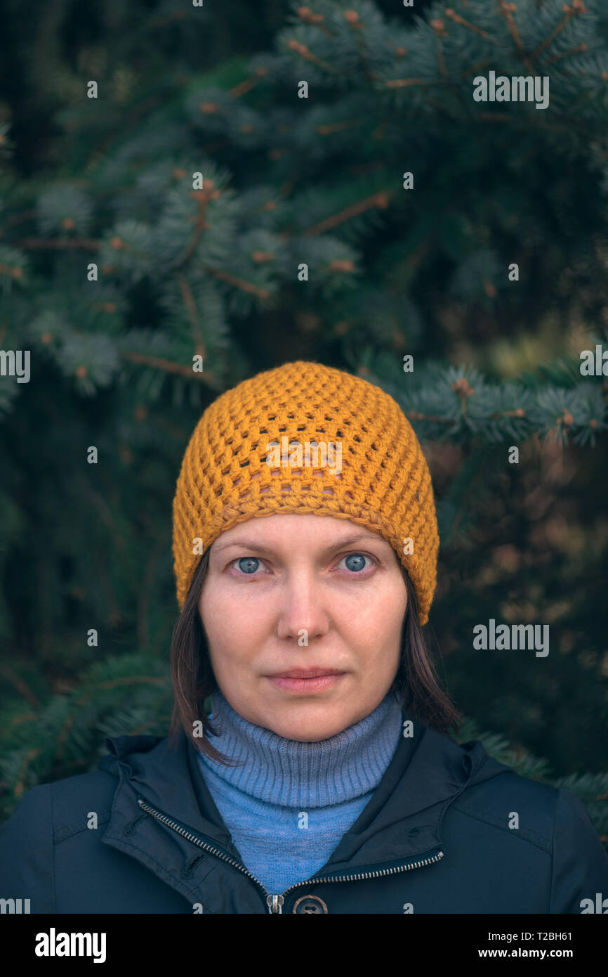 Schöne Frau in 40 s Porträt Porträt im Park, lässiger weibliche Person mit gelber Kappe vor Tannenbaum posiert an sonnigen Frühlingstag. Stockfoto