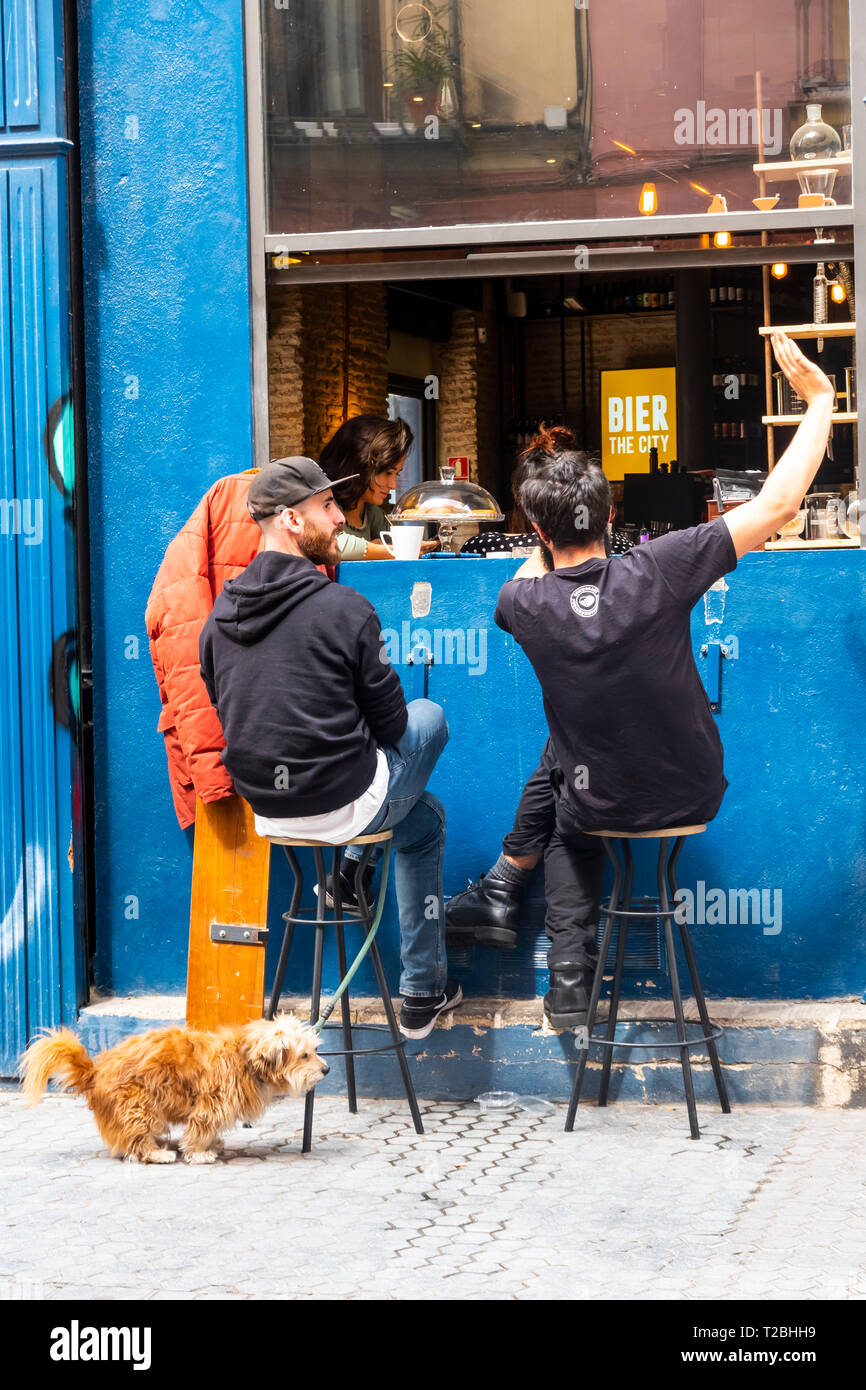 Zwei junge Männer und ein Hund vor einer Bar in Sevilla Stockfoto
