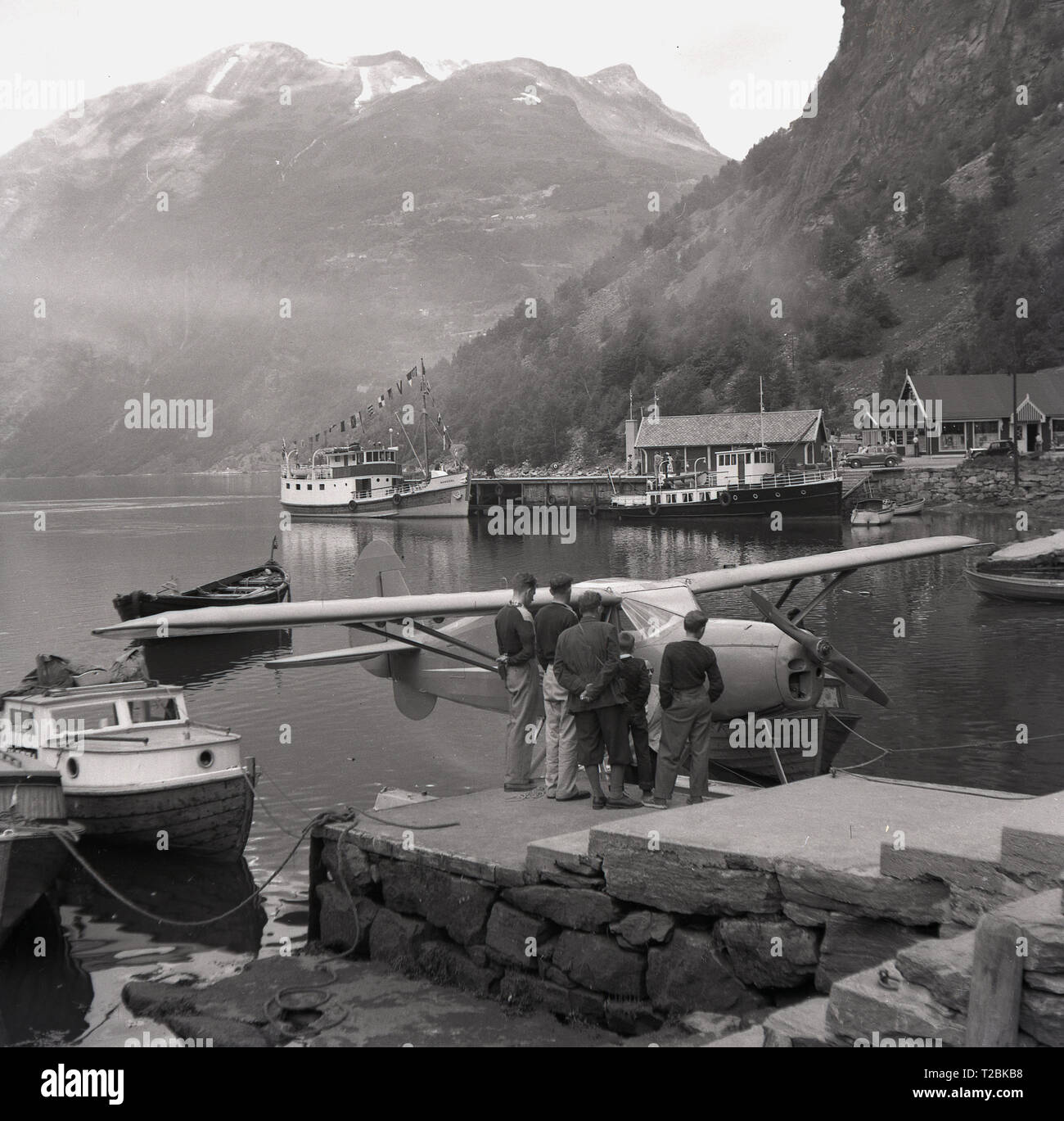 1950, historische, Männer und Jungen an einer Norwegischen an einem Fjord an eine kleine Feste - Flügel mit dem Wasserflugzeug angetrieben oder "wasserflugzeug" durch Schritte im Hafen in der Nähe von Narvik, Norwegen günstig Suchen suchen. Stockfoto