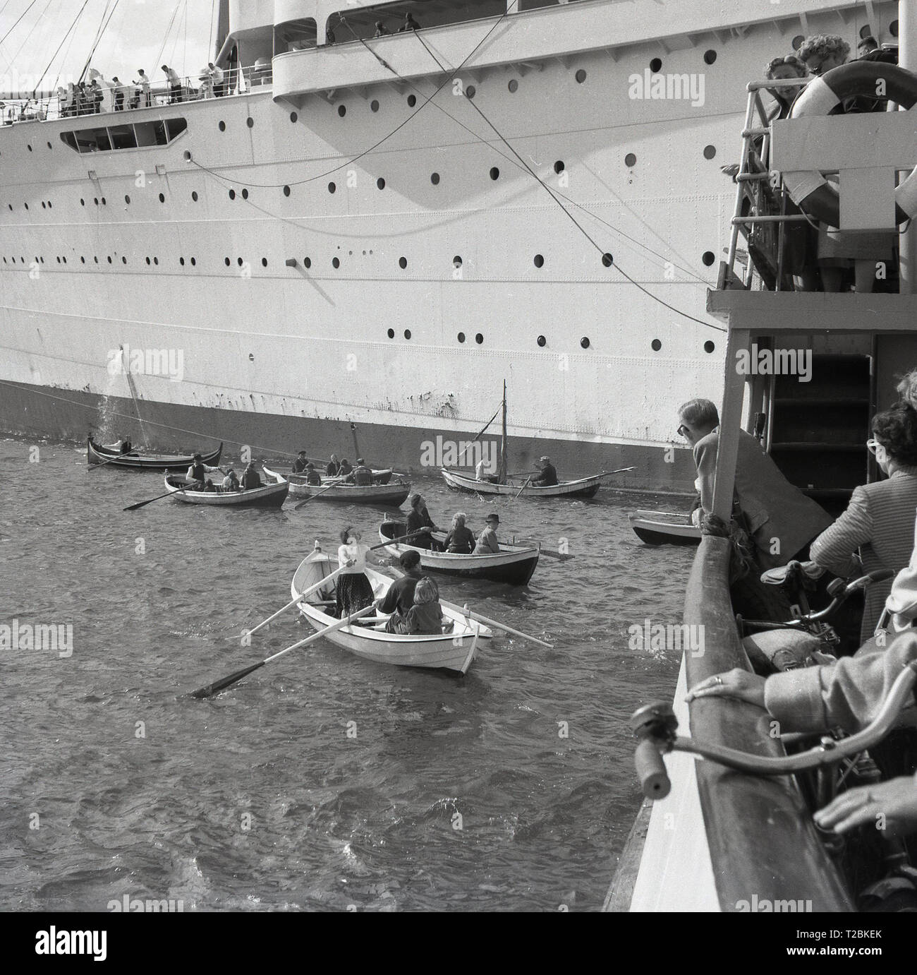 1950, historische, Passagiere in kleine Ruderboote oder Rettungsboote neben einem großen Kreuzfahrt Dampfschiff. Stockfoto
