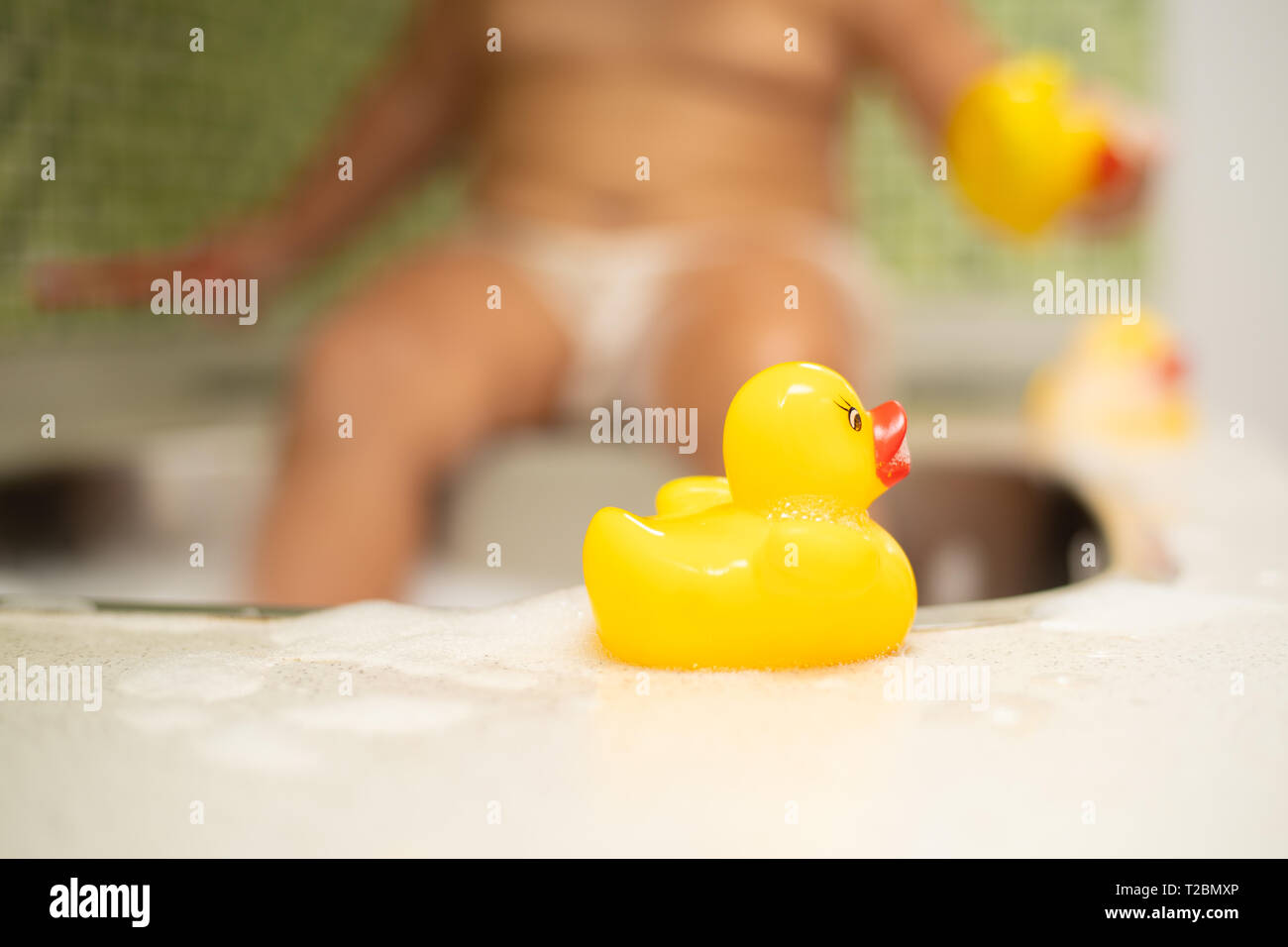 Gelbe Ente, im Hintergrund ein Kind in die Spüle ist unscharf. Stockfoto