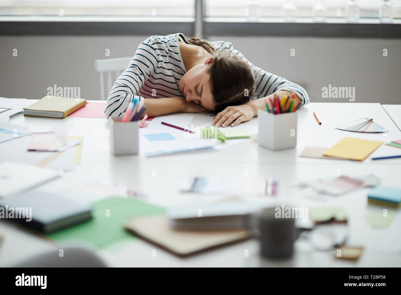 Porträt des zeitgenössischen junge Frau schlafen auf Tabelle bei der Arbeit, Platz kopieren Stockfoto