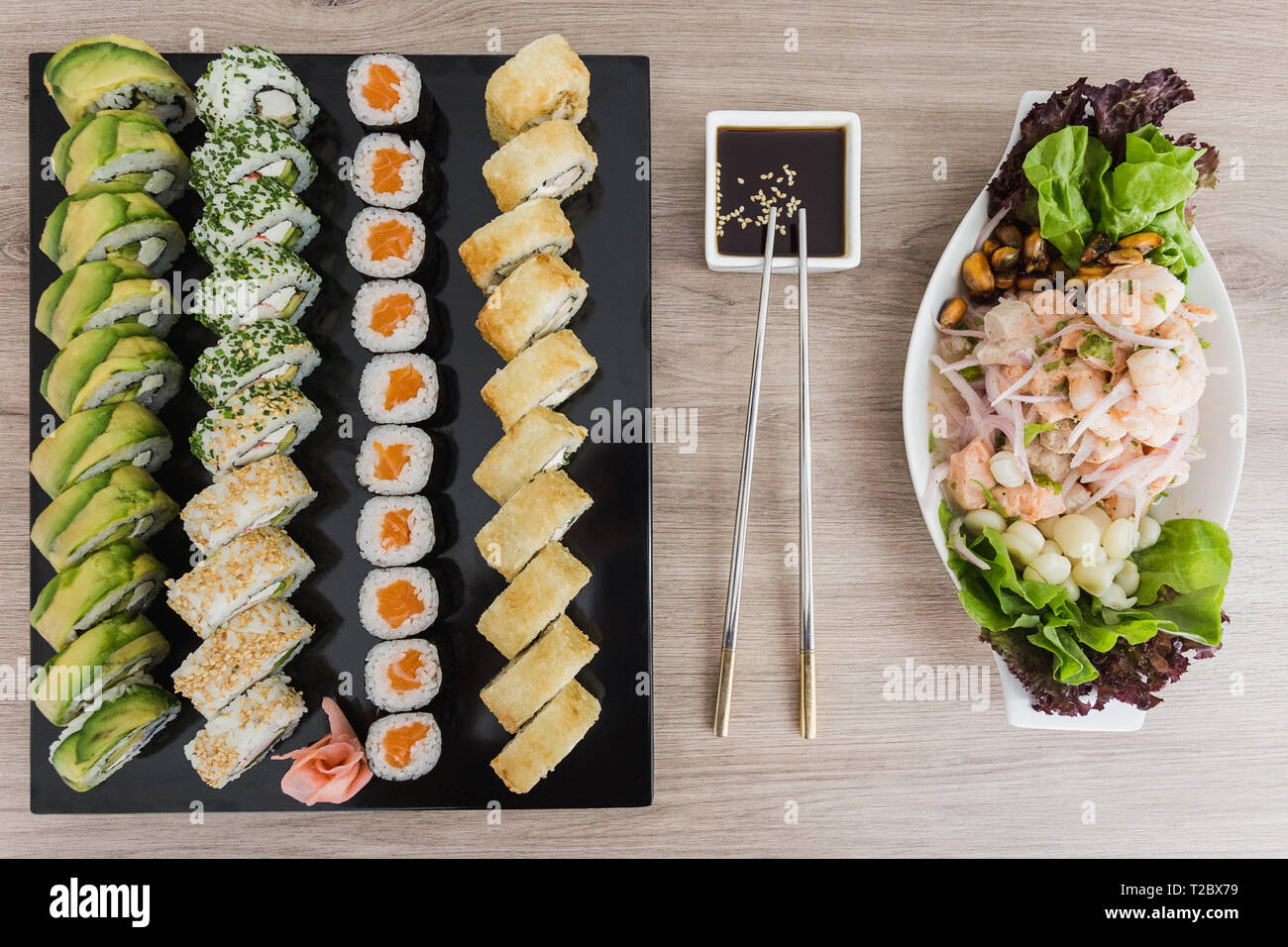 Sushi Rollen mit Ceviche und Sojasauce auf einem Holztisch Stockfoto