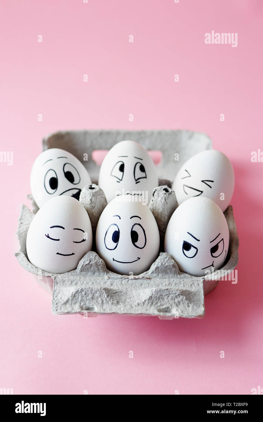 Lustige Ostereier mit Mimik. Eier mit verschiedenen Gesichter auf rosa Hintergrund. Stockfoto