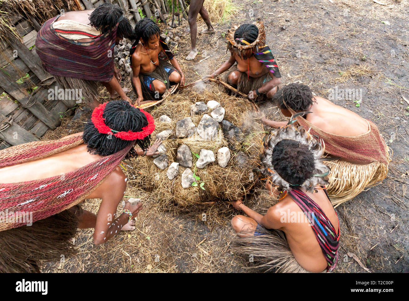 Wamena, Indonesien - Januar 9, 2010: Dani Frauen kochen in ein Loch mit heißen Steinen gefüllt. Das Baliem Valley, Papua Neu Guinea. Stockfoto