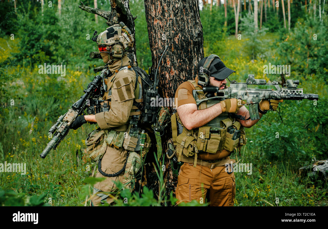 Airsoft Männer mit Gewehren stehen Rücken an Rücken. Soldaten stand auf einem Hügel und auf Abruf im Wald Stockfoto