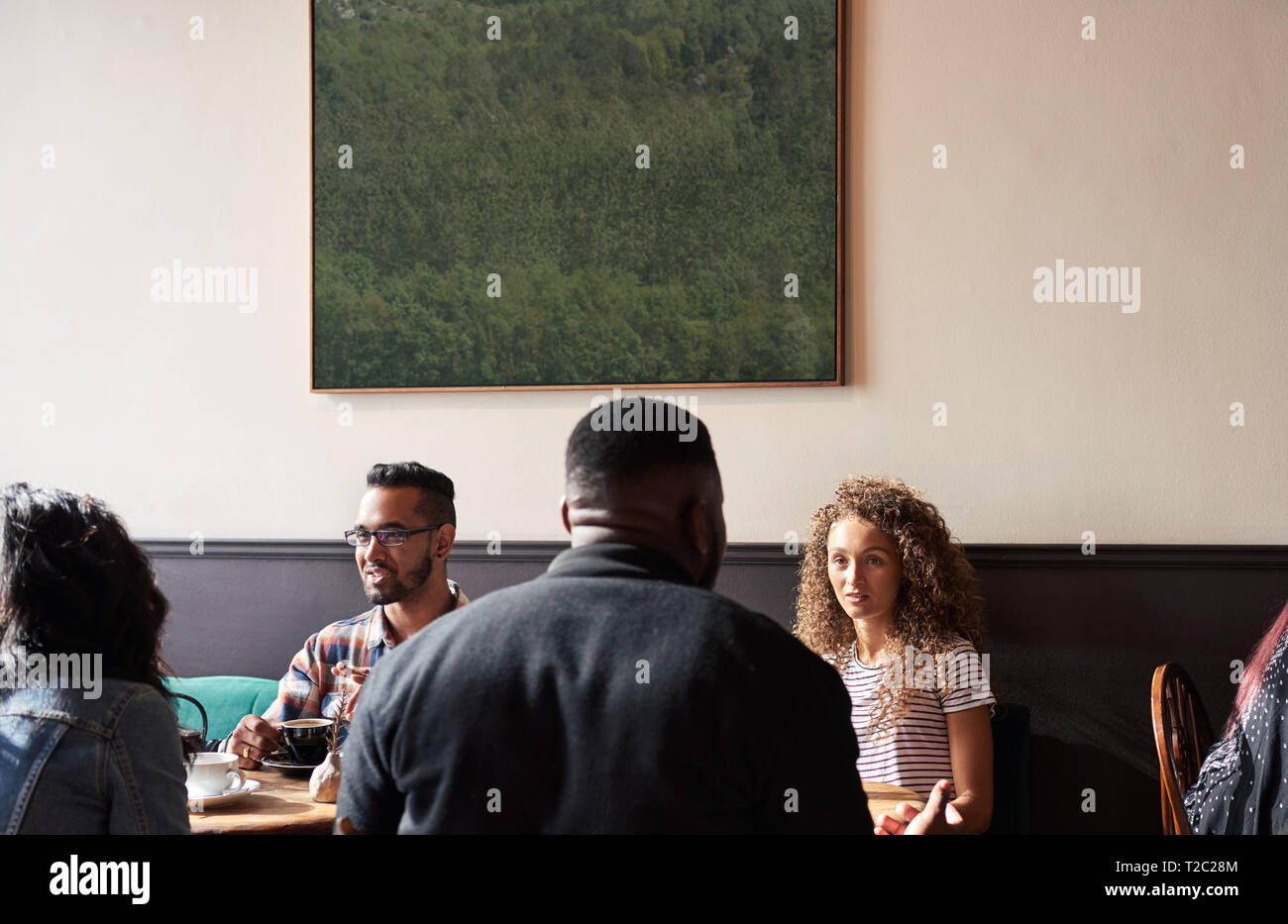 Gruppe von diverse junge Leute zusammen, die an Tischen sitzen in einem angesagten Cafes Kaffee trinken und reden Stockfoto