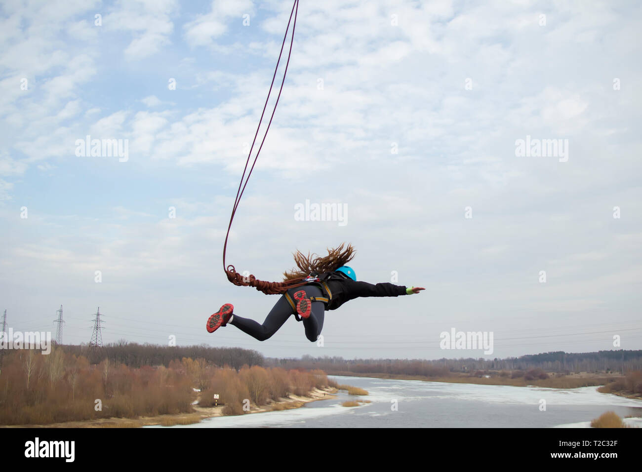 Belarus, Gomel, März 08, 2019. Das Springen von der Brücke zum Seil. Ropejumping. Gefährliche Hobbys. mutige Frau Jumping von der Brücke gegen den Himmel Stockfoto