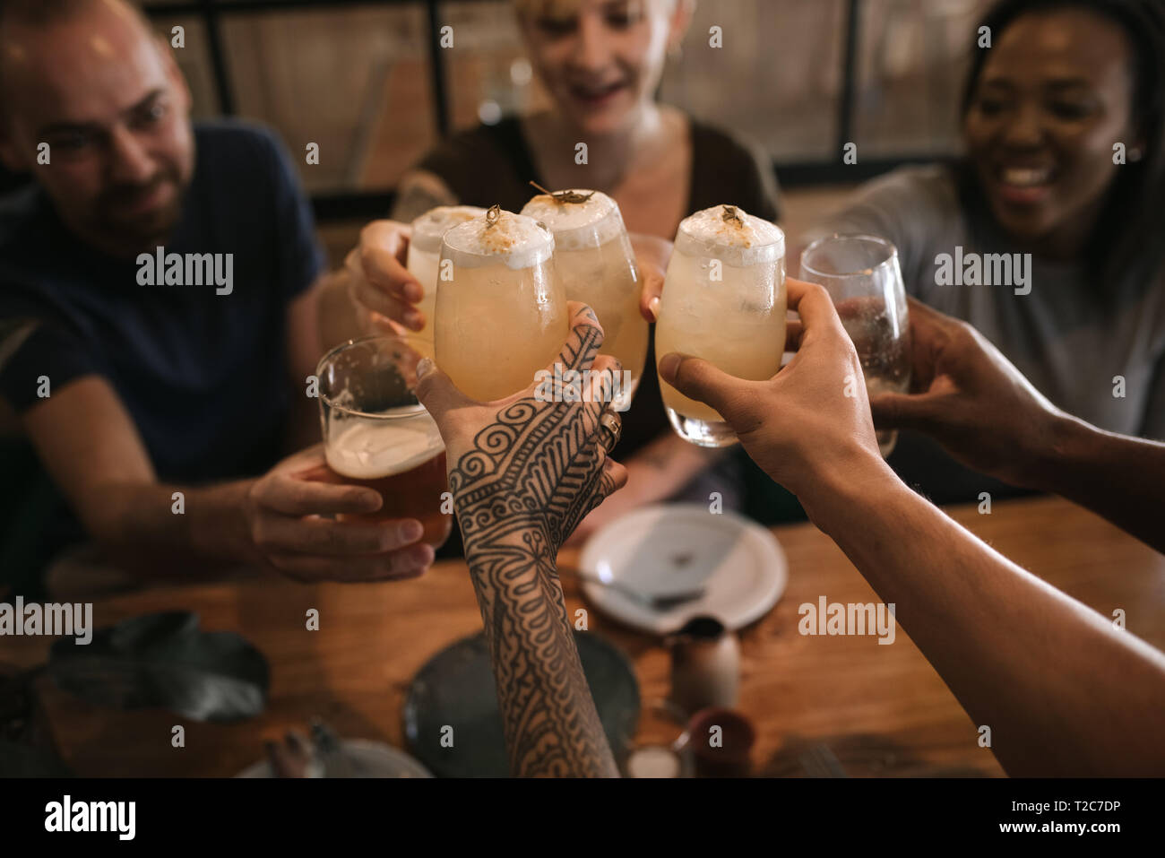 Vielfältige Gruppe von Freunden, die zusammen das Toasten mit Getränken, während sitzen zusammen in einer Bar in der Nacht Stockfoto
