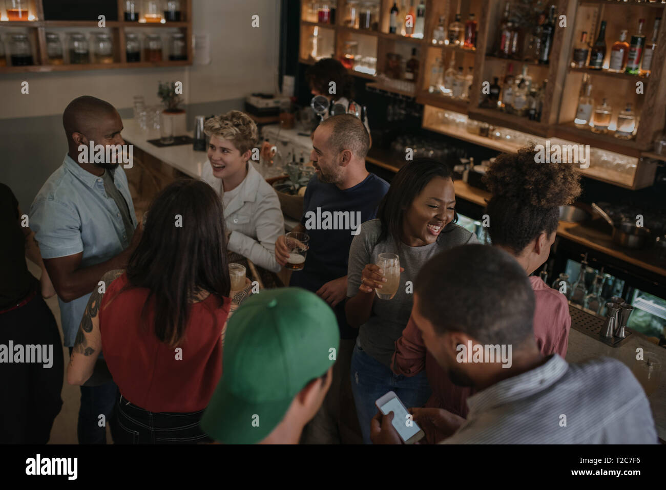 Hohe Winkel von einer Gruppe von jungen Leuten in einer Bar in der Nacht zusammen reden über Getränke Stockfoto