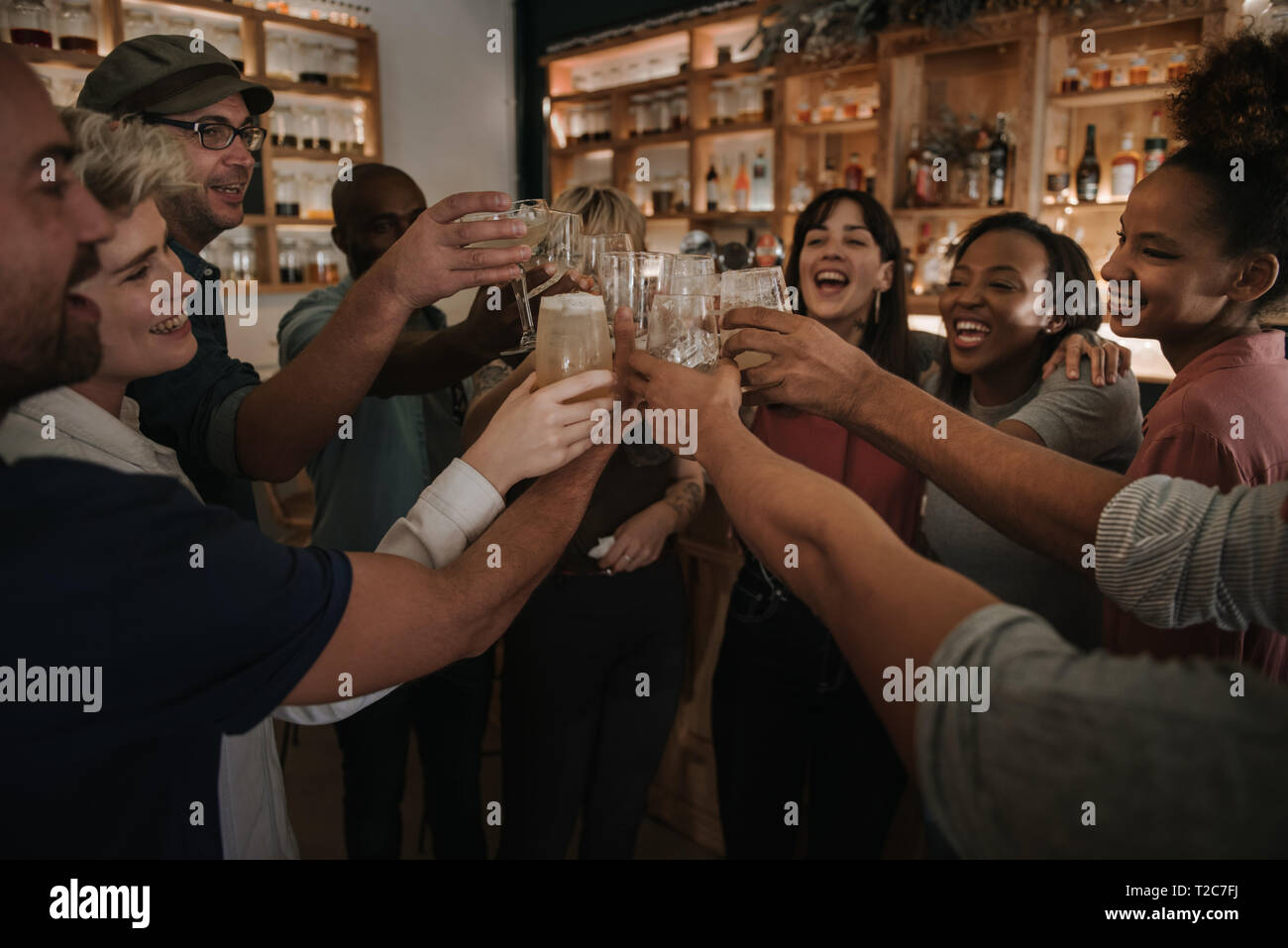 Vielfältige Gruppe von jungen Freunde jubeln mit Getränken während heraus zusammen hängen in einer Bar am Abend Stockfoto