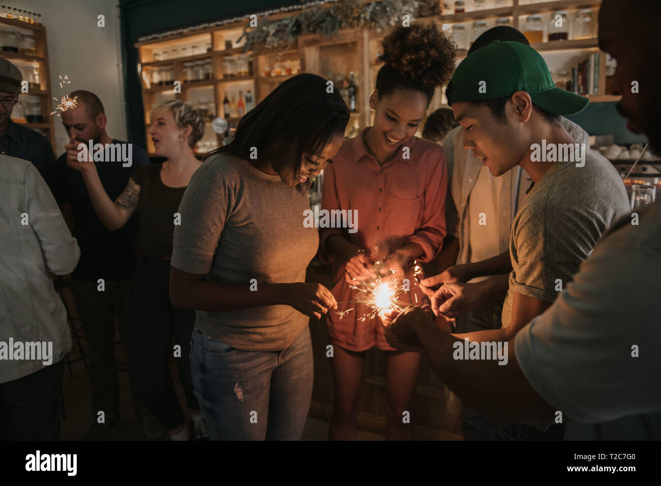 Gruppe von verschiedenen jungen Freunde Beleuchtung Wunderkerzen beim haben eine lustige Nacht gemeinsam in eine trendige Bar Stockfoto