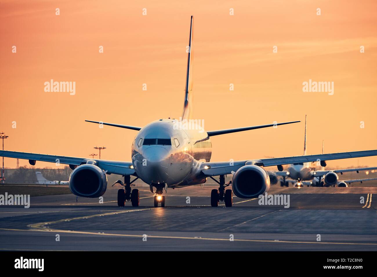 Flugzeuge in der Zeile Rollen zur startbahn zum Abheben. Verkehr an der geschäftigen Flughafen bei Sonnenuntergang. Stockfoto