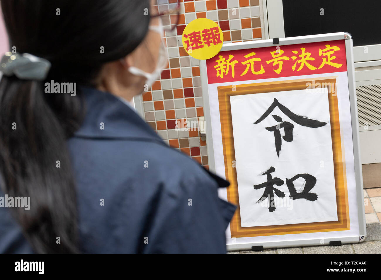 Tokio, Japan. 1 Apr, 2019. Tokio, Japan. 01 Apr, 2019. Eine Frau geht vorbei an einem Schild mit dem japanischen Kanji''Reiwa'' als neuen Namen der nächsten Kaiserzeit, in der Innenstadt von Tokio. Die japanische Chief Cabinet Secretary Yoshihide Suga angekündigt ''Reiwa'' als neue Kaiserzeit Name heute, 1. April. Die neue Ära beginnt am 1.Mai, wenn der Kronprinz Naruhito besteigt den Thron, nachdem sein Vater, Kaiser Akihito, formal dankt am 30. April. Credit: Rodrigo Reyes Marin/LBA/Alamy leben Nachrichten Stockfoto