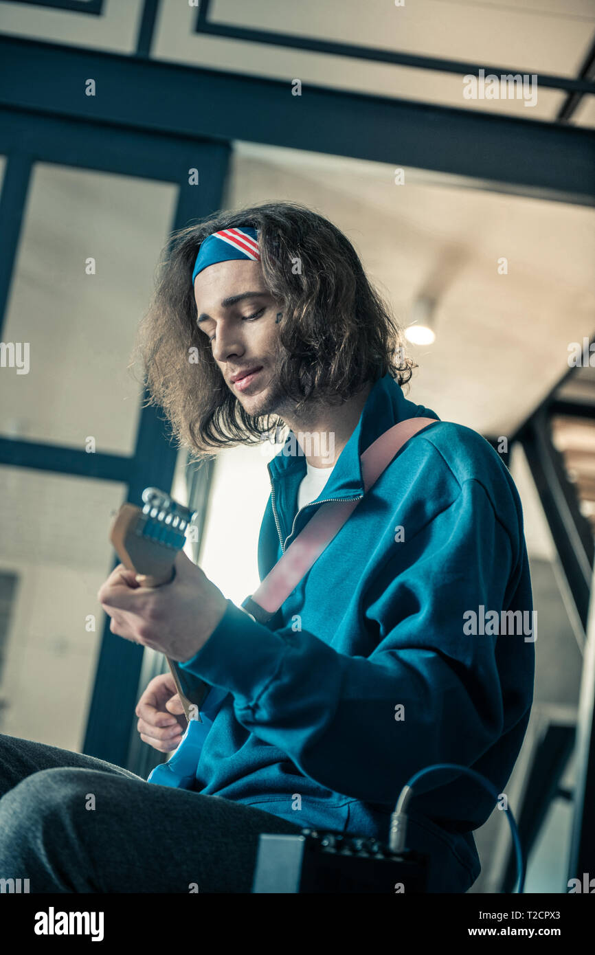 Friedliche hübscher junger Mann in Bandana Fokussierung auf Fähigkeiten seines Instruments Stockfoto