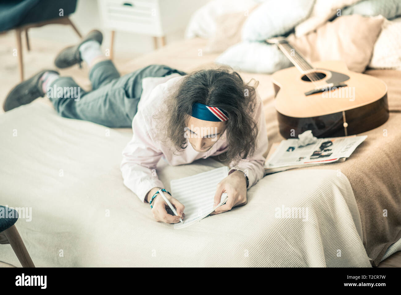 Dunkelhaarige konzentrierte sich Künstler im Bett zu liegen und arbeiten bei der Erstellung Stockfoto
