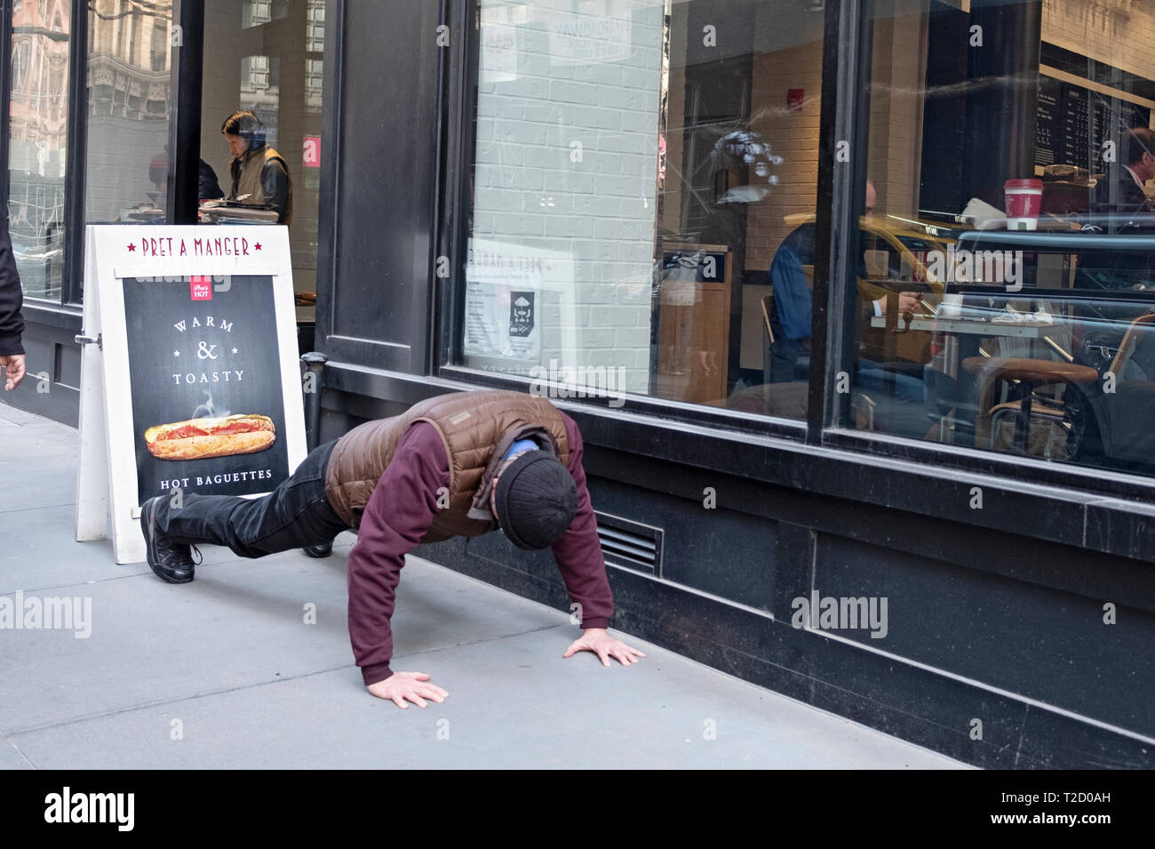 Ein unbekannter Mann hat pushups außerhalb eines Restaurants auf der East 12th Street am Broadway in Greenwich Village, Manhattan, New York City. Stockfoto