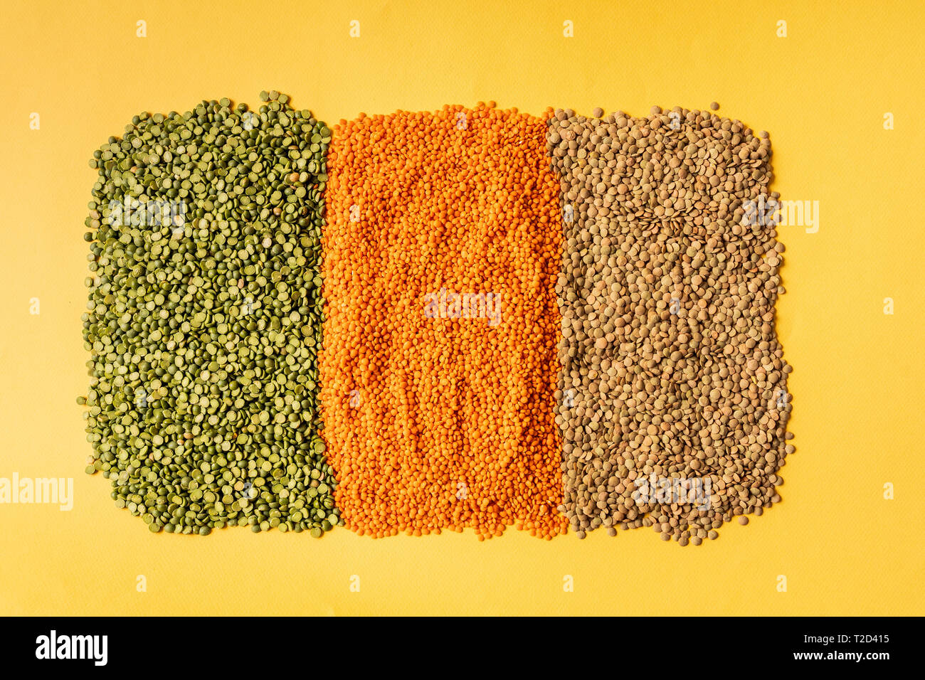 Hintergrund mit kleinen orange, gelbe und grüne Linsen Samen der jährlichen Legumen plant, sie sind reich an pflanzlichen Proteinen. Auf gelben Hintergrund. Stockfoto