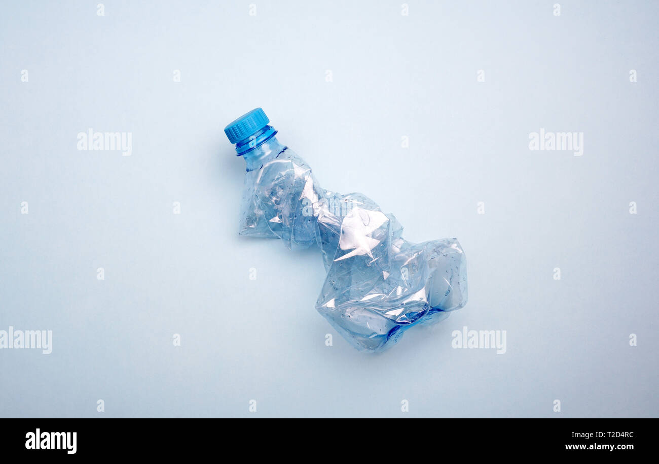 Zerknitterte Plastikflasche auf blauem Hintergrund. Kreative minimalen Begriff von Wasser und Meer Verschmutzung Stockfoto