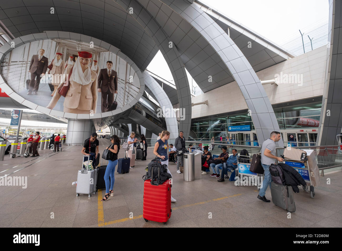 Passagiere mit einem rollenden Fälle in der Abflughalle auf dem Internationalen Flughafen von Dubai in den Vereinigten Arabischen Emiraten Stockfoto