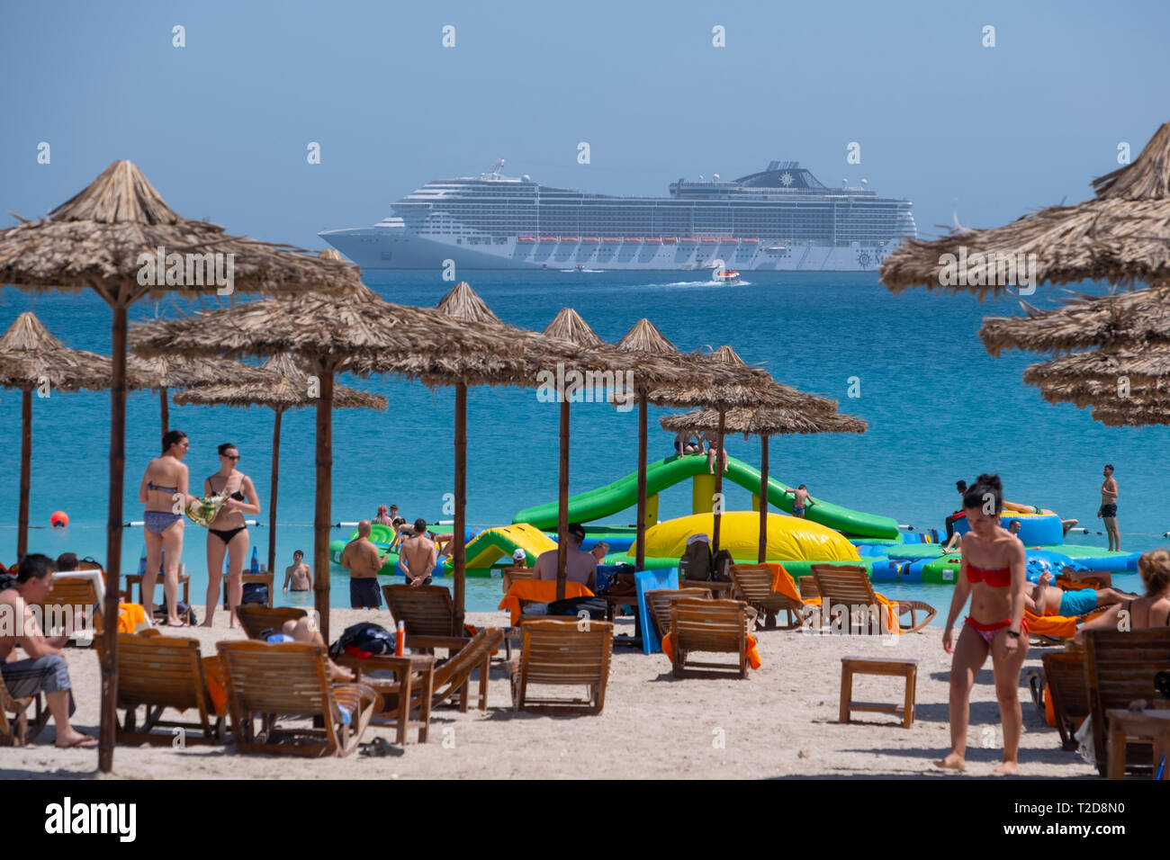 Die Menschen genießen den Strand bei Sir Bani Yas Island mit dem Kreuzfahrtschiff MSC Splendida auf See im Hintergrund Stockfoto