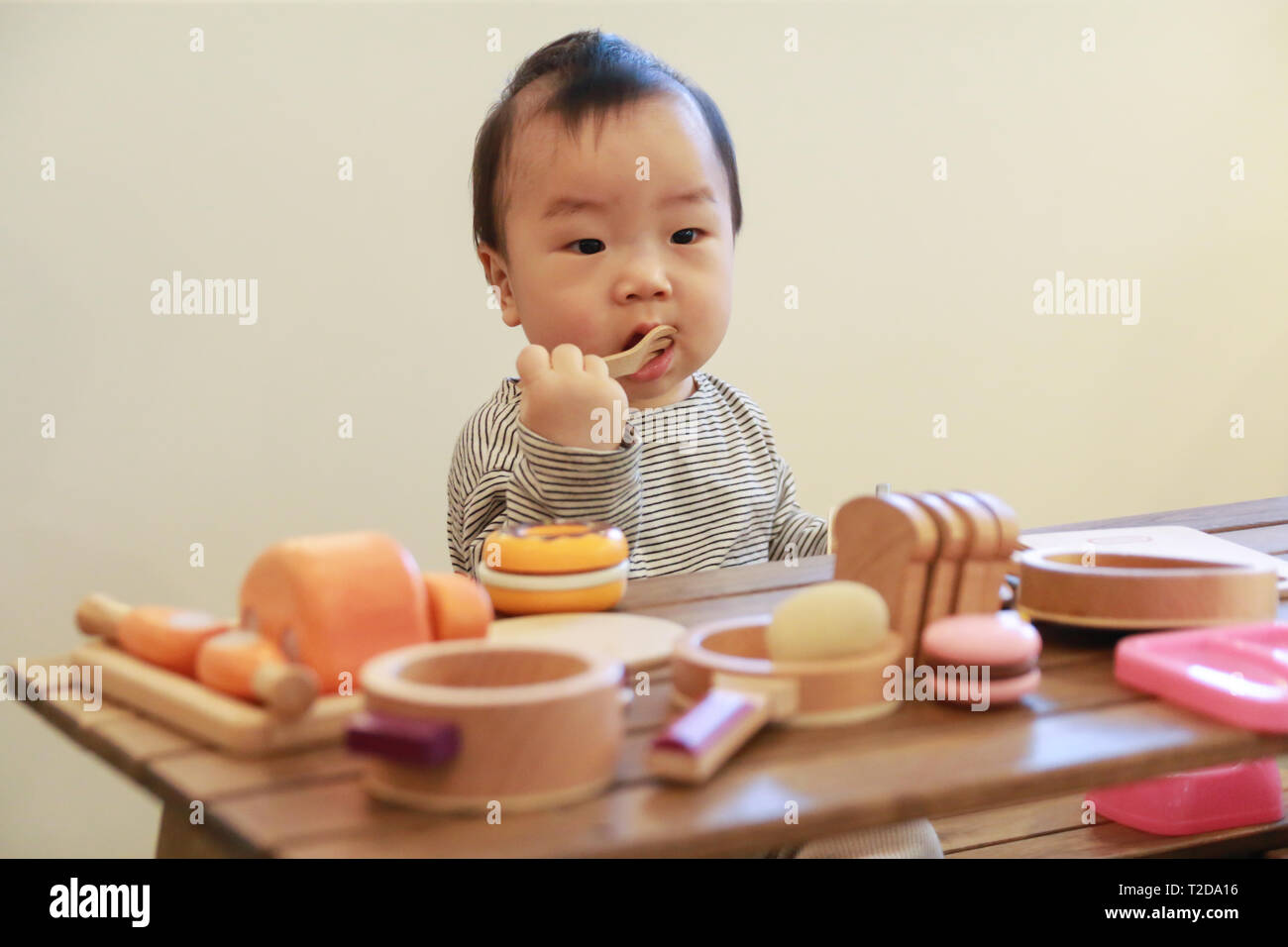 Asiatische Baby spielt mit Campingausrüstung Spielzeug Werkzeuge auf dem Holztisch in Baby Cafe Stockfoto