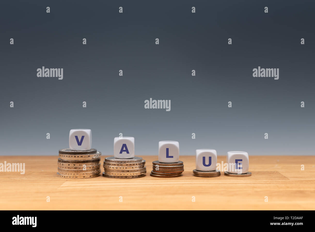 Symbol für abnehmende Wert. Würfel auf Stapel von Münzen Form das Wort "Wert". Stockfoto