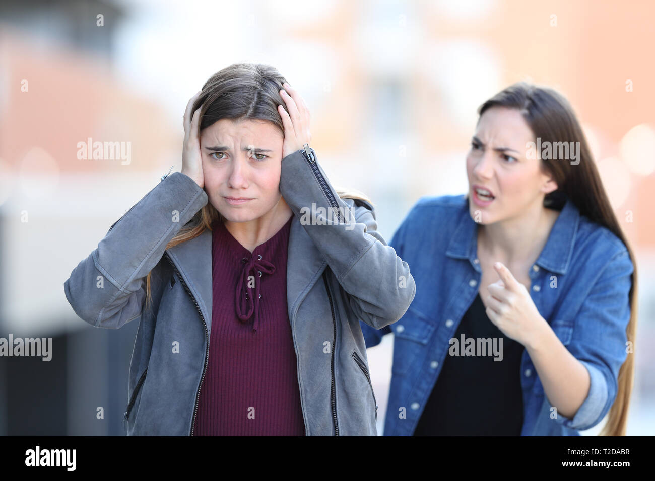 Böse Mädchen ihre traurige Freund, der an der Kamera auf der Straße sieht Schelte Stockfoto