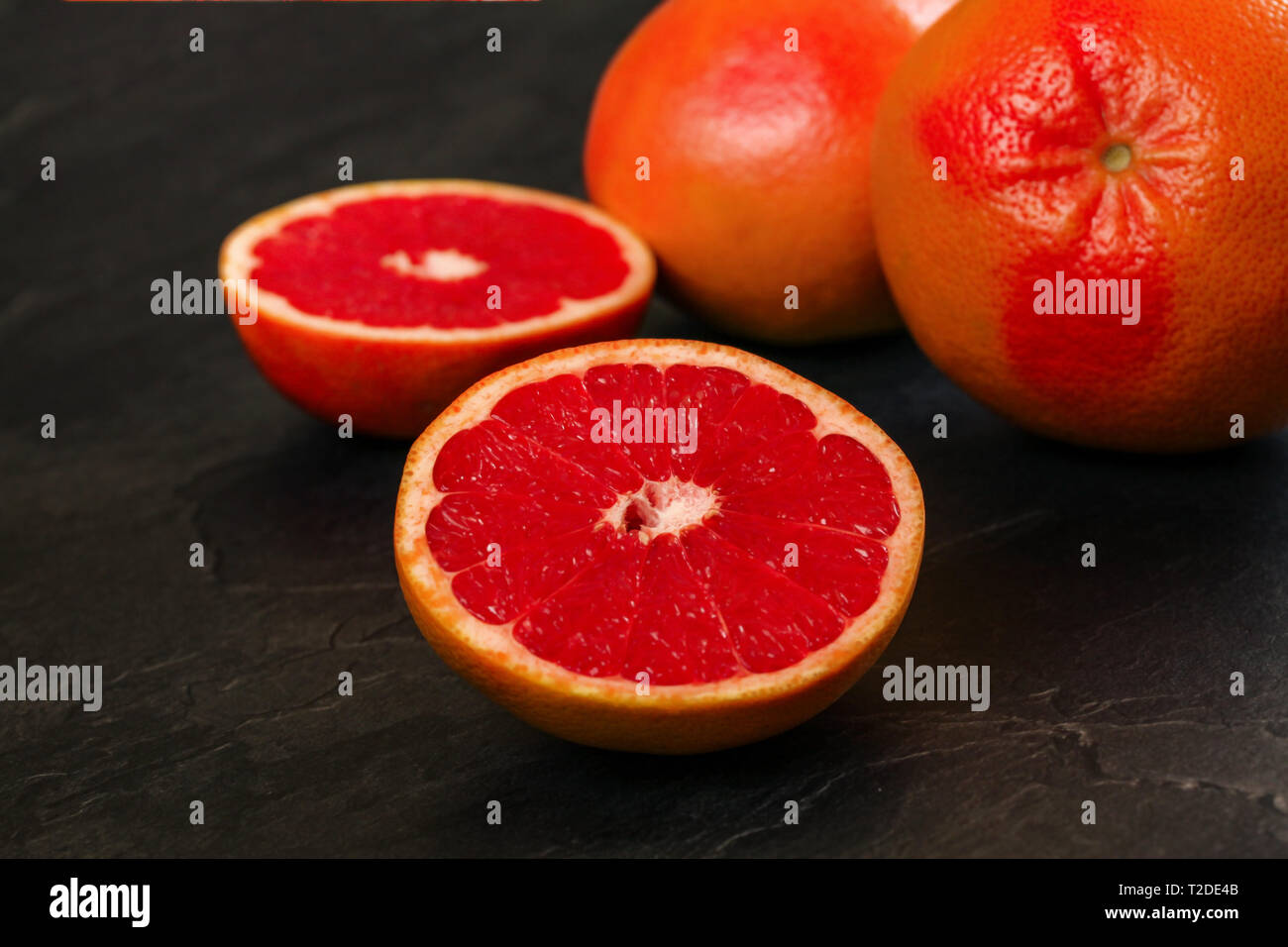 Detail der Rote Grapefruit eine Citrus halbiert, auf schwarzem Schiefer wie Board. Stockfoto
