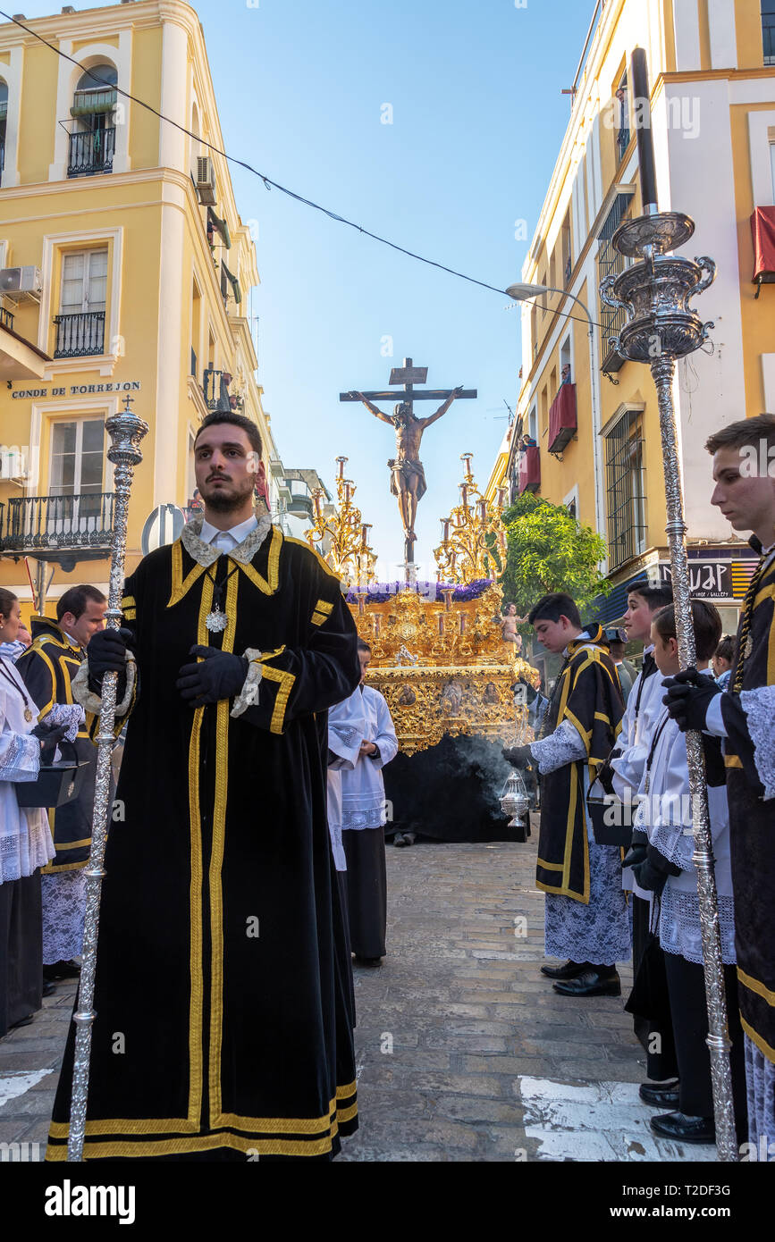 Sevilla, Spanien - 27. März: die Menschen in prunkvollen Kleidung mit einem goldenen Schwimmer mit Jesus am Kreuz in Sevilla, Spanien am 27. März 2018 Stockfoto