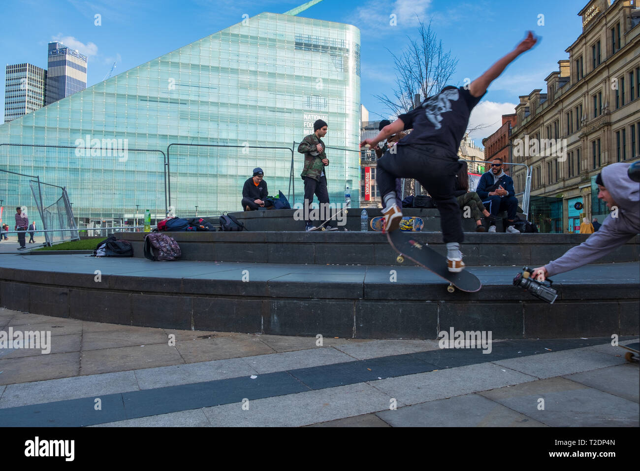 Manchester, Vereinigtes Königreich - Februar 16, 2019: Jungs im Teenageralter skateboarding und Video miteinander Dreharbeiten vor der National Football Museum Stockfoto