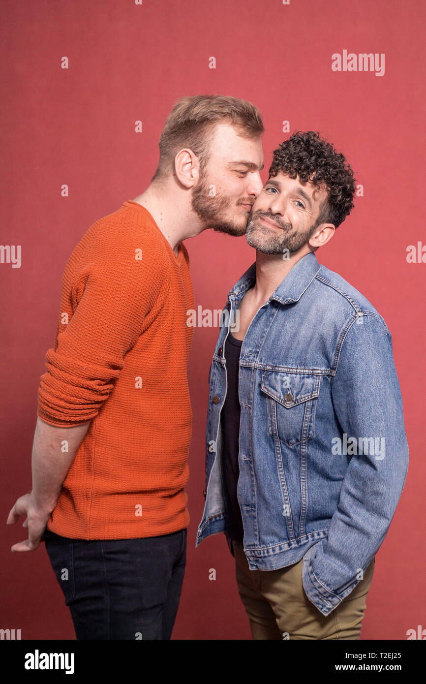 Zwei Männer, ein schwules Paar intim. Kuss auf die Wange. Eine Kamera  schaut sich lächelnd Stockfotografie - Alamy
