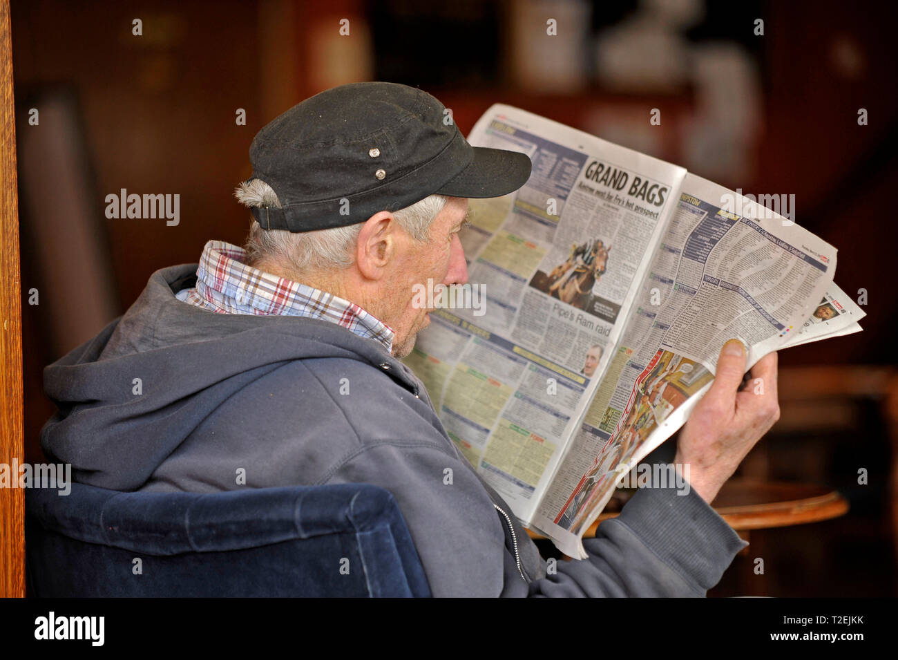 Profil von älteren Mann in legerer Kleidung lesen Der racing Seiten eines täglichen Red Top Zeitung Stockfoto