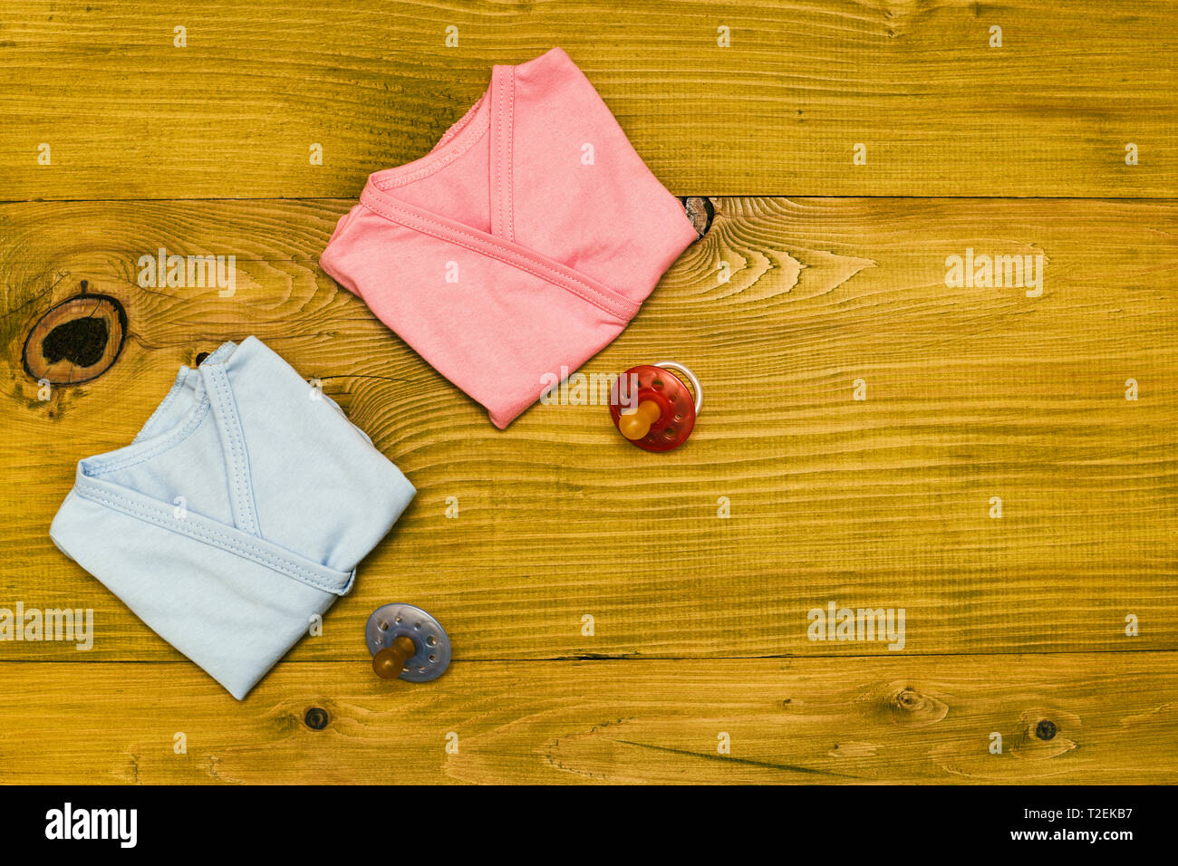 Baby Kleidung und Schnuller für Jungen und Mädchen auf Holztisch. Baby Ankündigung Konzept. Getönten Foto. Stockfoto