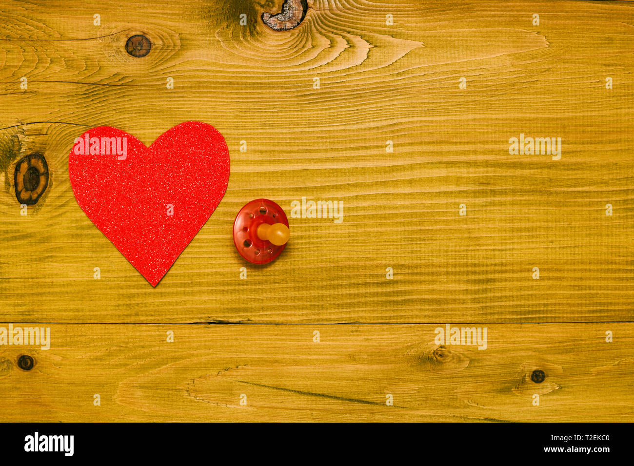 Rosa Schnuller für Baby Girl mit Herz Form auf Holztisch. Baby Ankündigung Konzept. Getönten Foto. Stockfoto