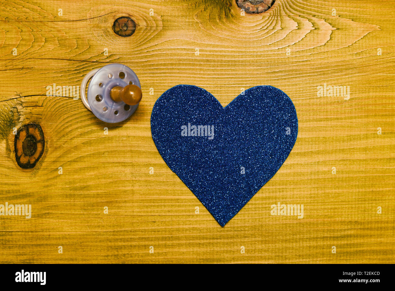 Blau Schnuller für baby boy mit Herz Form auf Holztisch. Baby Ankündigung Konzept. Getönten Foto. Stockfoto