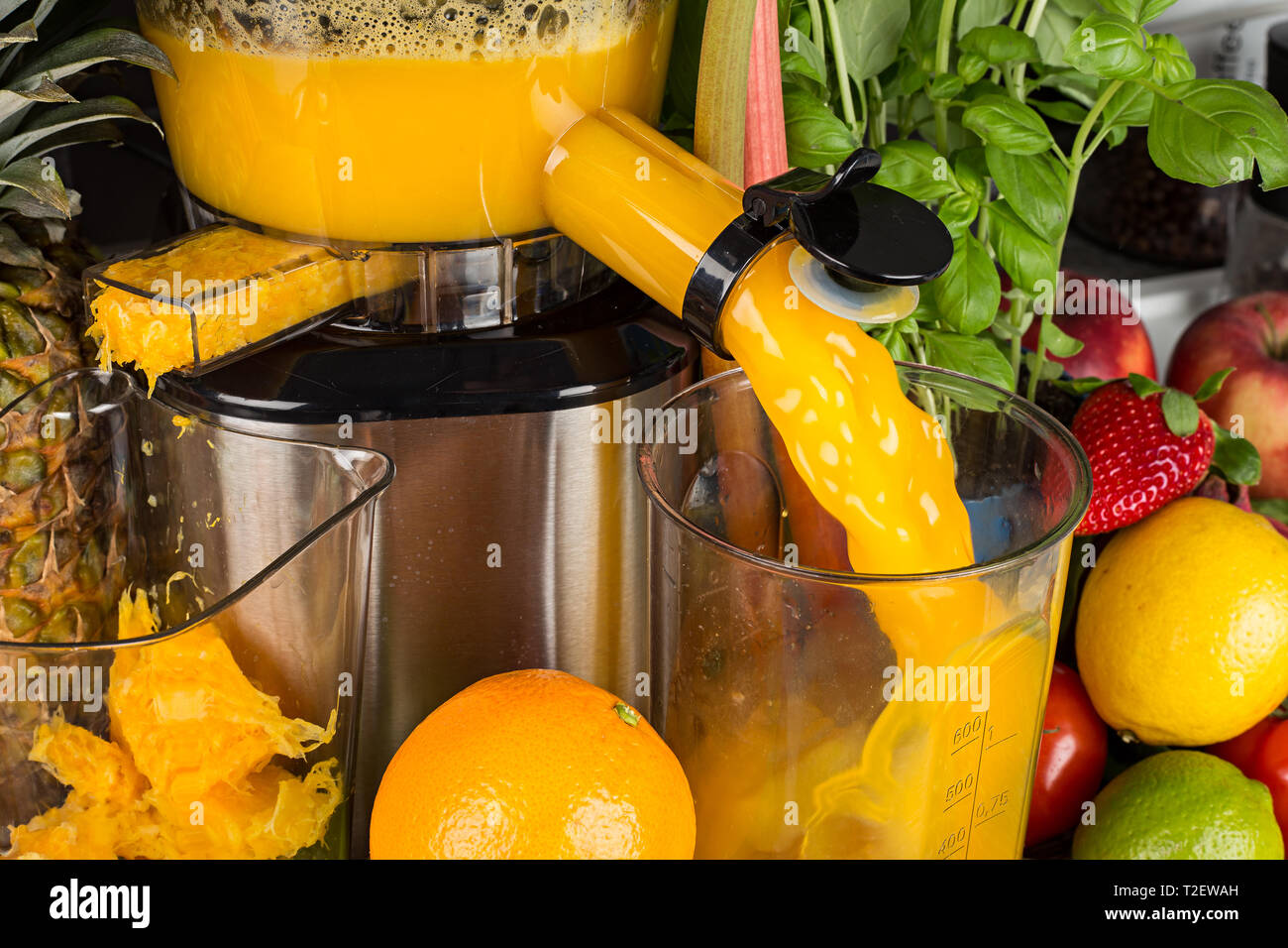 Langsam Entsafter in der Küche mit vielen Früchten und Gemüse der orange Vitamin Saft gesunder Lebensstil Ernährung Konzept Hintergrund Stockfoto