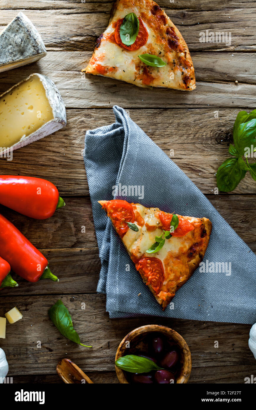 Pizza auf Holz mit Zutaten. Pizza mit Käse, Tomaten und Basilikum. Rustikale italienische Pizza Stockfoto