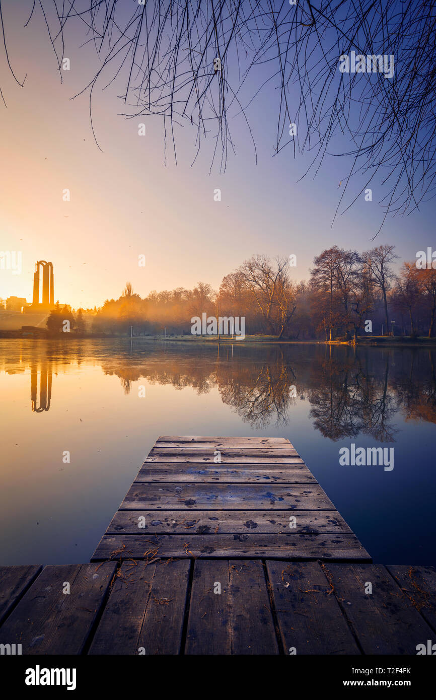 Schönen Sonnenaufgang im Winter auf einem See mit einem Ponton im Vordergrund und im Hintergrund ein moument Stockfoto