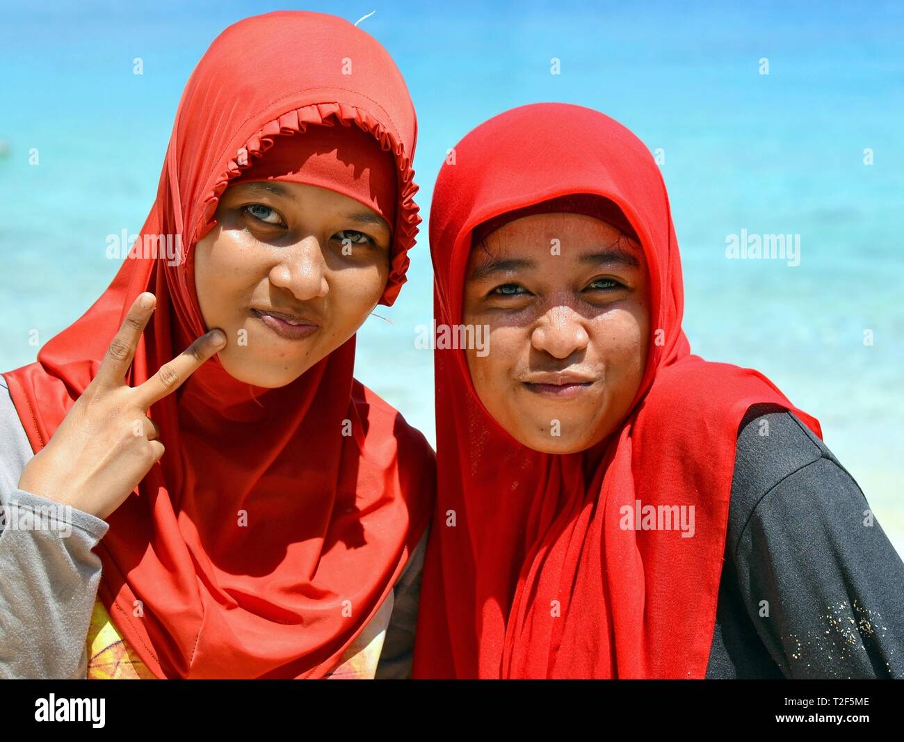 Zwei indonesische muslimischen Frauen (Mutter und Tochter) tragen rote hijabs und das V-Zeichen machen. Stockfoto