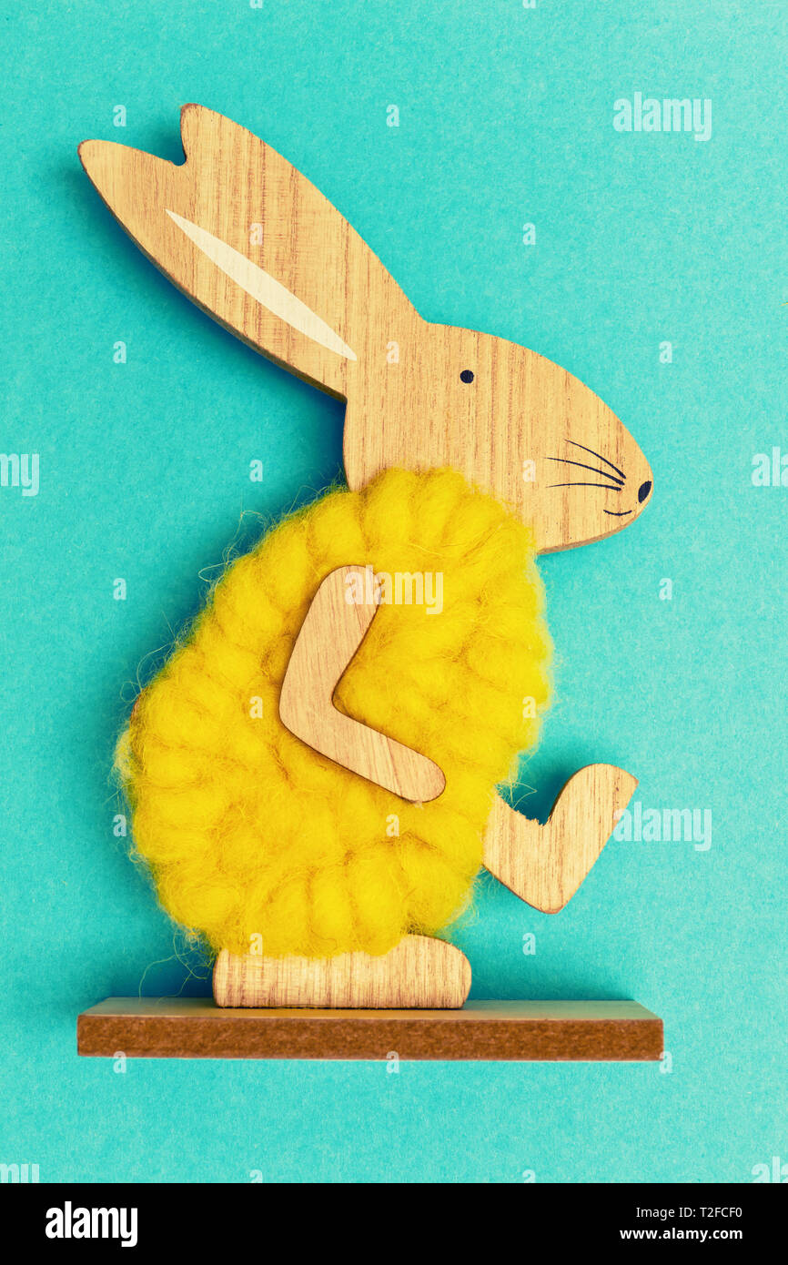 Zu Fuß aus Holz Osterhase mit gelben Fell auf blau türkis Hintergrund, retro, flach Stockfoto