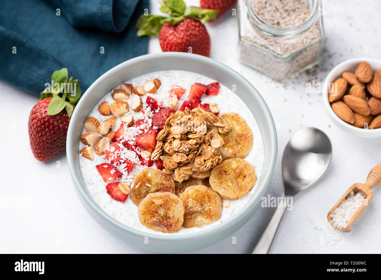 Smoothy Schüssel mit Banane, Erdbeere, Müsli, Nüsse auf weißer Tisch. Detailansicht. Konzept der gesunde vegetarische Diät, Gewichtsverlust, ausgewogene Ernährung Stockfoto