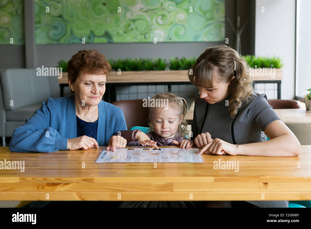 Weibliche Familie mit drei Generationen von Frauen Enkelin Mutter und Großmutter beobachtete die Speisekarte in einem Restaurant. Stockfoto