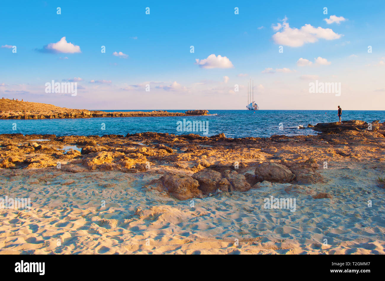 Bild von atemberaubender Nissi Beach in Agia Napa, Zypern. Gelb Sand und Riffe gegen blau ruhig Wasser an einem warmen Abend im Herbst, kleine Wolken in der s Stockfoto