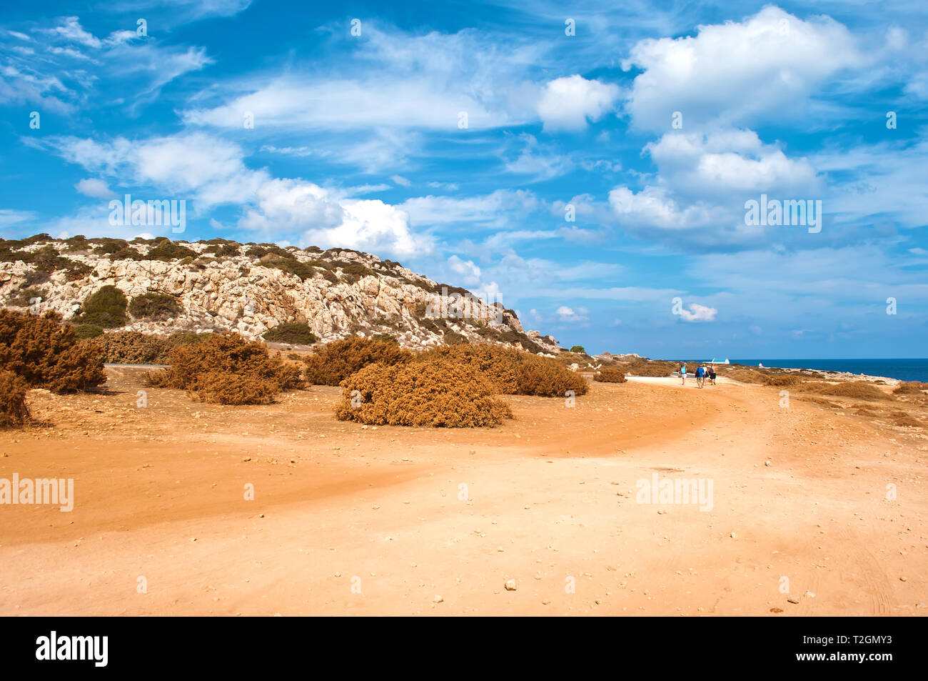 Bild von rauhem Kalkstein Küste in der Nähe von Kap Greco, Zypern. Cloudscape mit vielen weißen Wolken im Himmel, kargen orange sandigen Weg. Warmer Tag im Herbst Stockfoto
