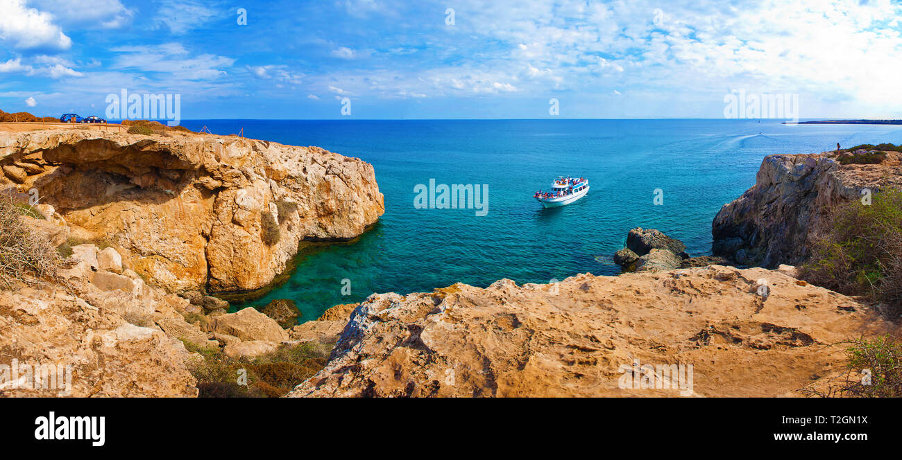 Bild mit Blick auf eine Bucht in der Nähe von Kap Greco, Zypern. Rock Küste in der Nähe von tiefen Grün transparent, azurblaues Wasser, ein weißes boot, Autos. Erstaunlich Clou Stockfoto