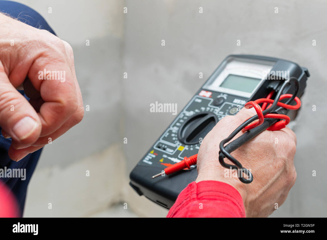 Elektriker mit Voltmeter bei der Installation von Steckdosen an der Wand im neuen Haus Stockfoto