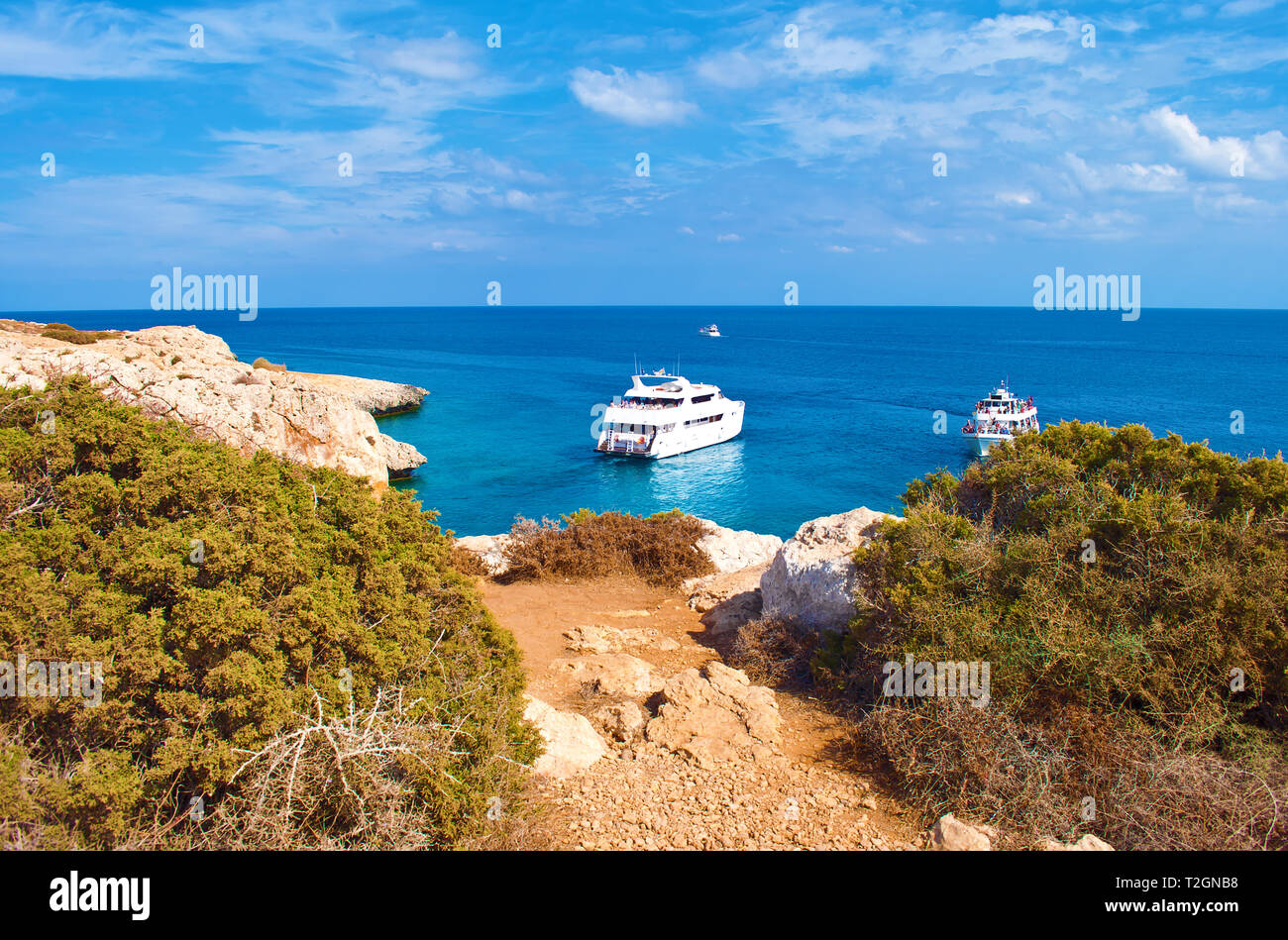 Bild des großen weißen Yachten im Wasser in der Nähe von Kap Greco, Zypern. Rock Küste in der Nähe von tiefen Grün transparent, azurblaues Wasser und hohen grünen Sträuchern. Warmer Tag Stockfoto